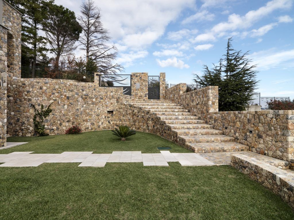 exteriors shots of a modern villa in foreground the masonry staircase that leads to iron gate