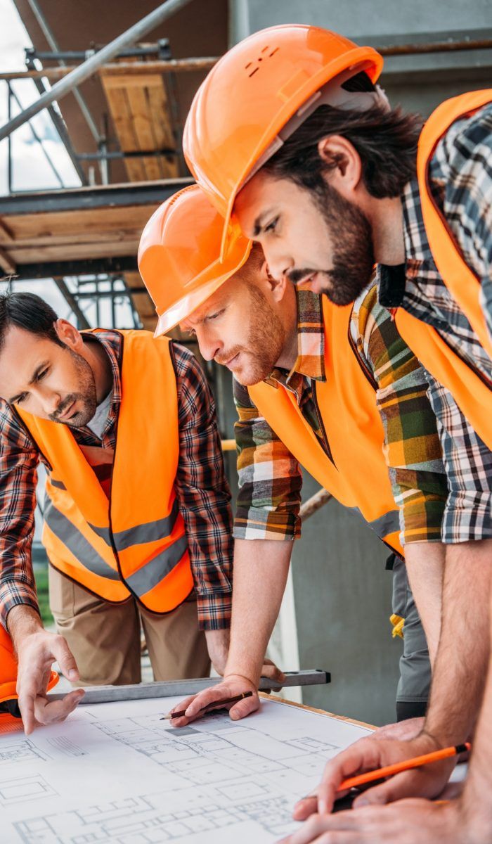 group of serious builders looking at building plan at construction site
